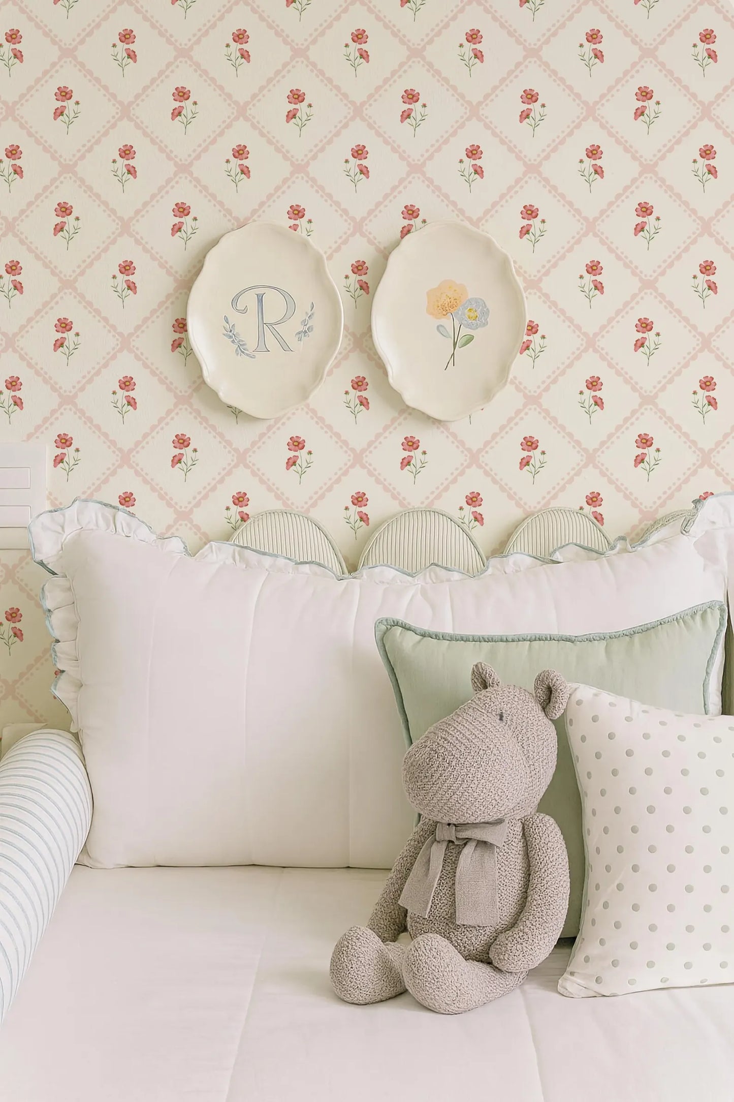 a cozy bedroom scene with a plush teddy bear sitting on a bed, surrounded by decorative pillows and a floral wallpaper.