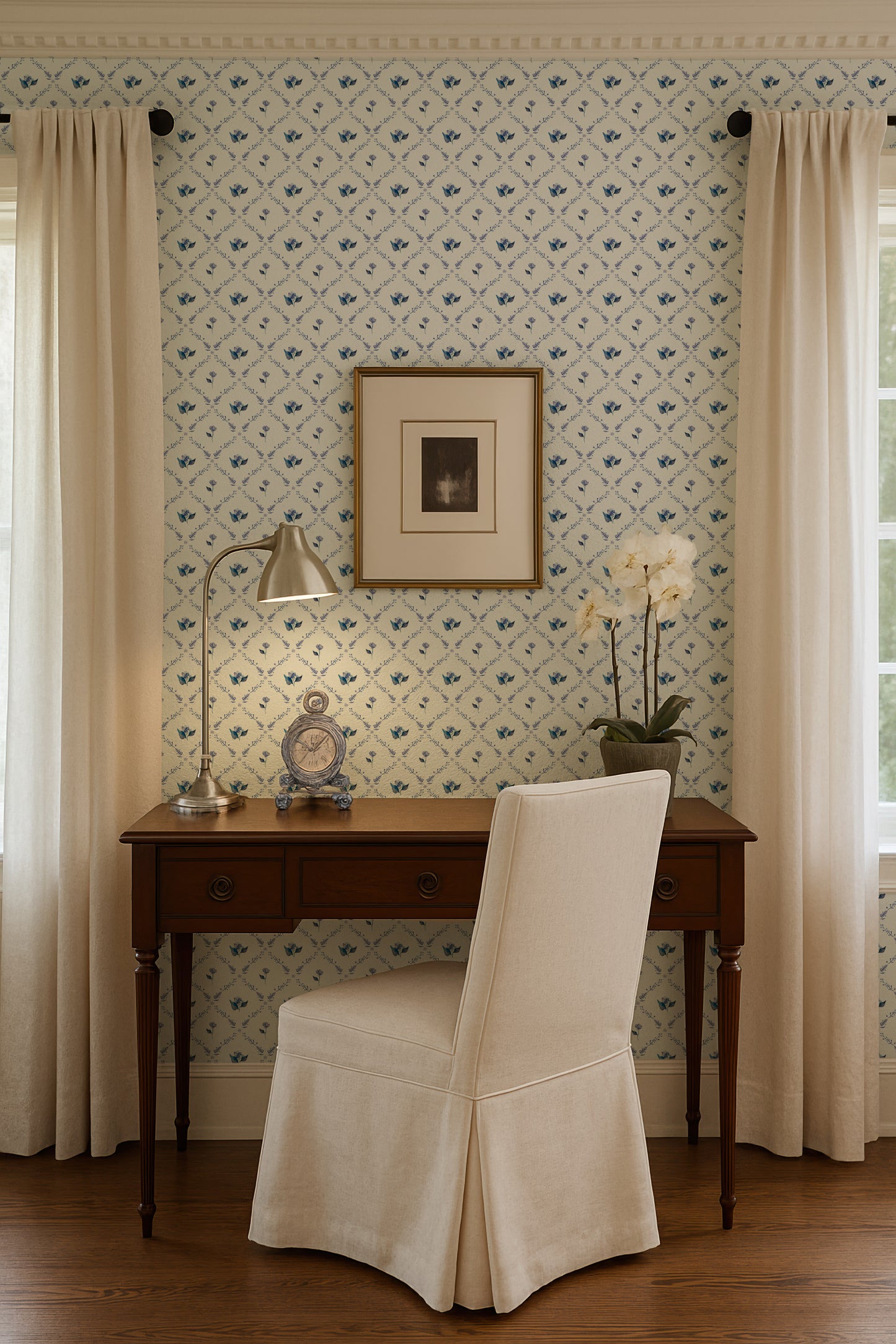 a cozy and well-decorated room with a wooden desk, a white chair, a framed picture, a lamp, and a vase with flowers.