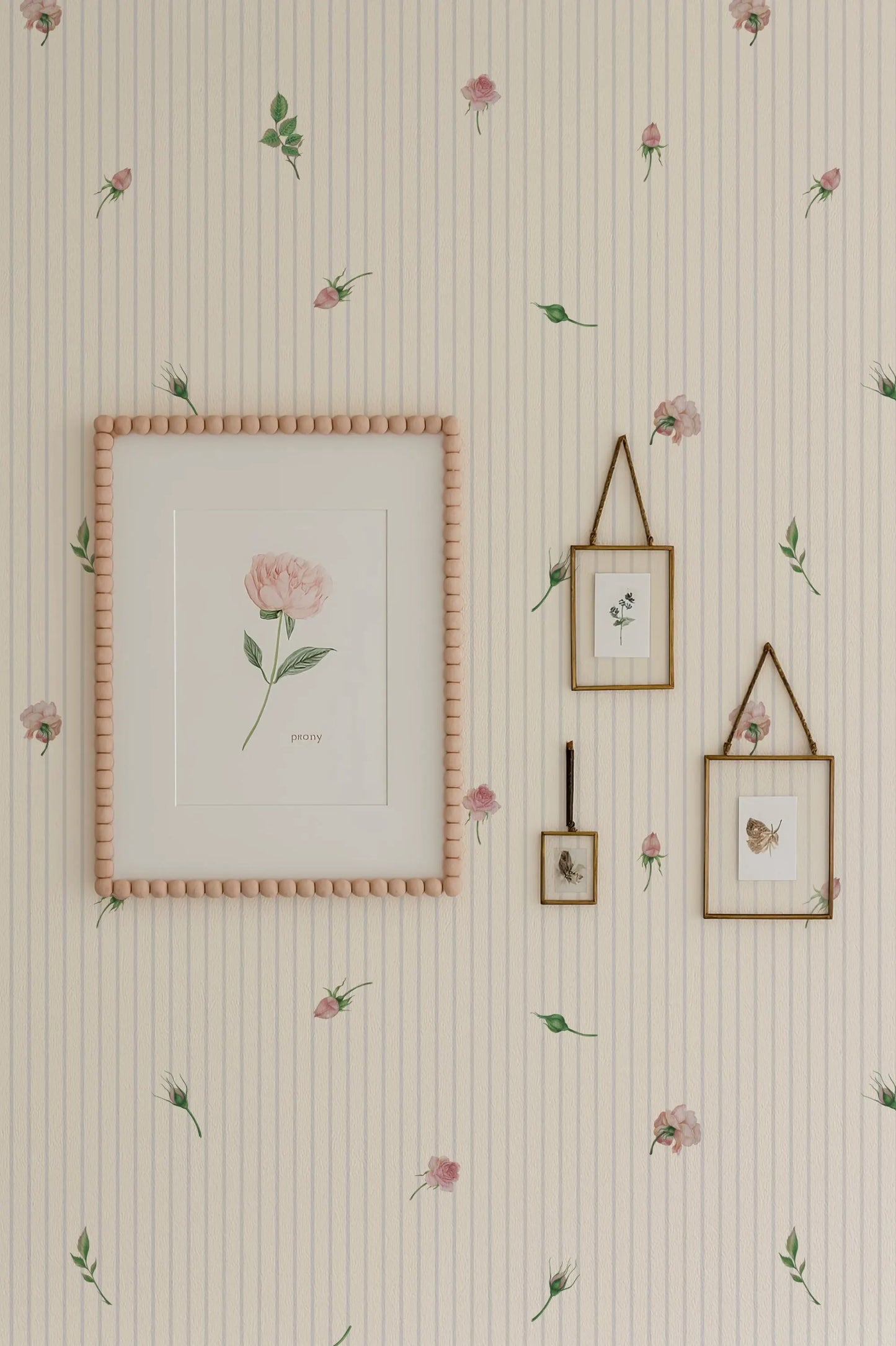 a wallpapered wall with a framed picture, two framed pictures, and a framed picture hanging on it. The wallpapered wall has a floral pattern, and the framed pictures and picture frame are also adorned with a floral pattern.
