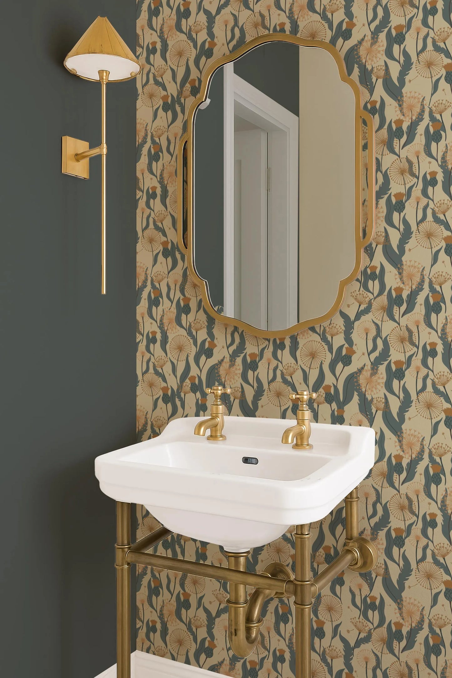 a bathroom with a white sink, a gold-framed mirror, and a gold-colored light fixture. The walls are adorned with a floral wallpaper pattern in shades of green and gold.
