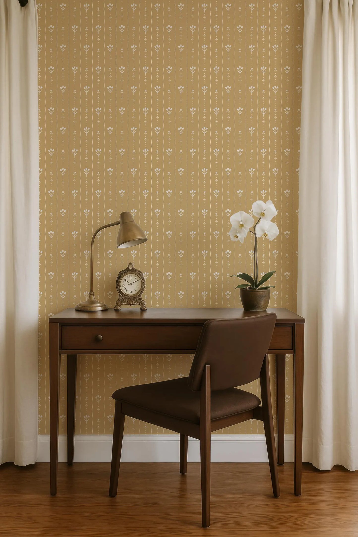 a wooden desk with a lamp, a clock, and a potted plant, situated in front of a wall with a patterned wallpaper.