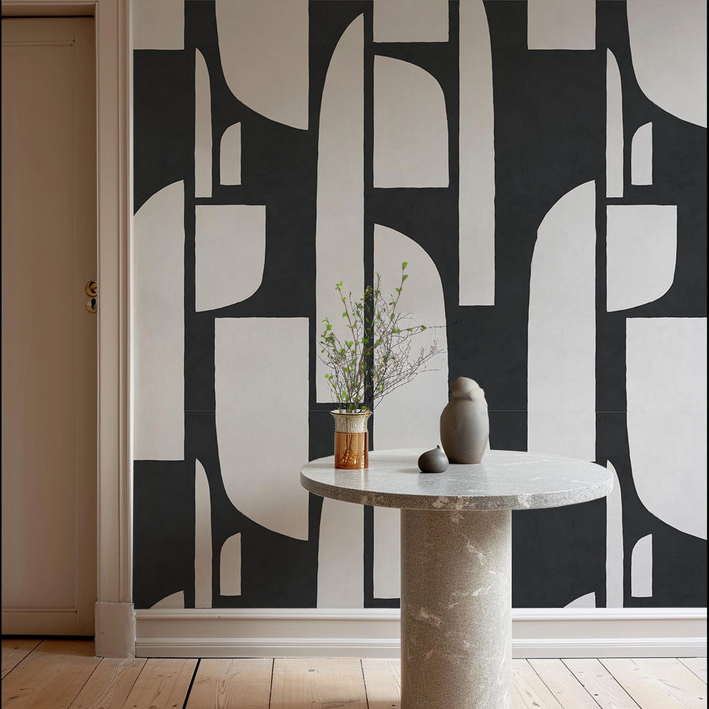 a table with a vase on it in front of a wall with black and white