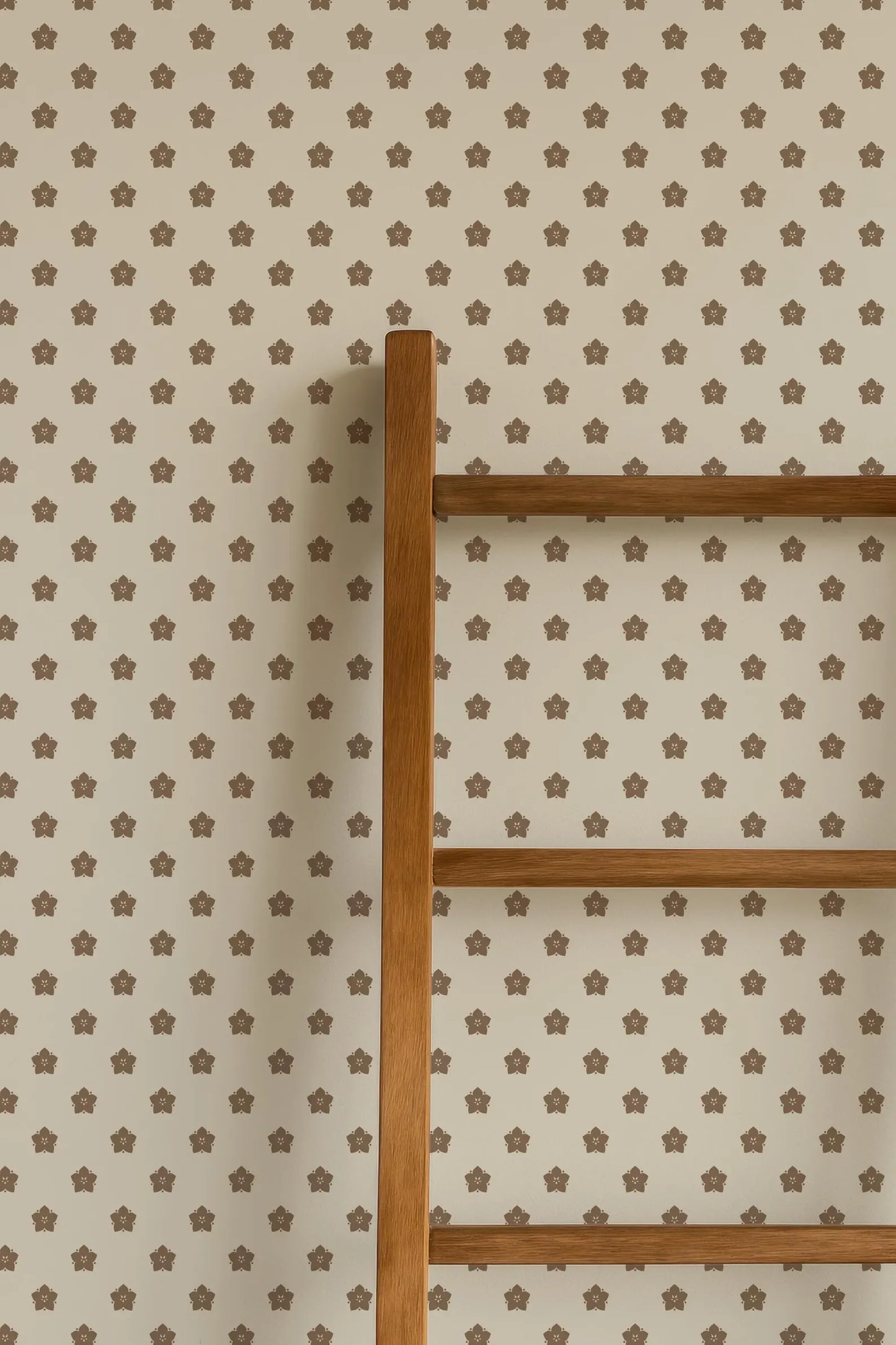 a wooden ladder against a wall with a repeating pattern of brown stars.