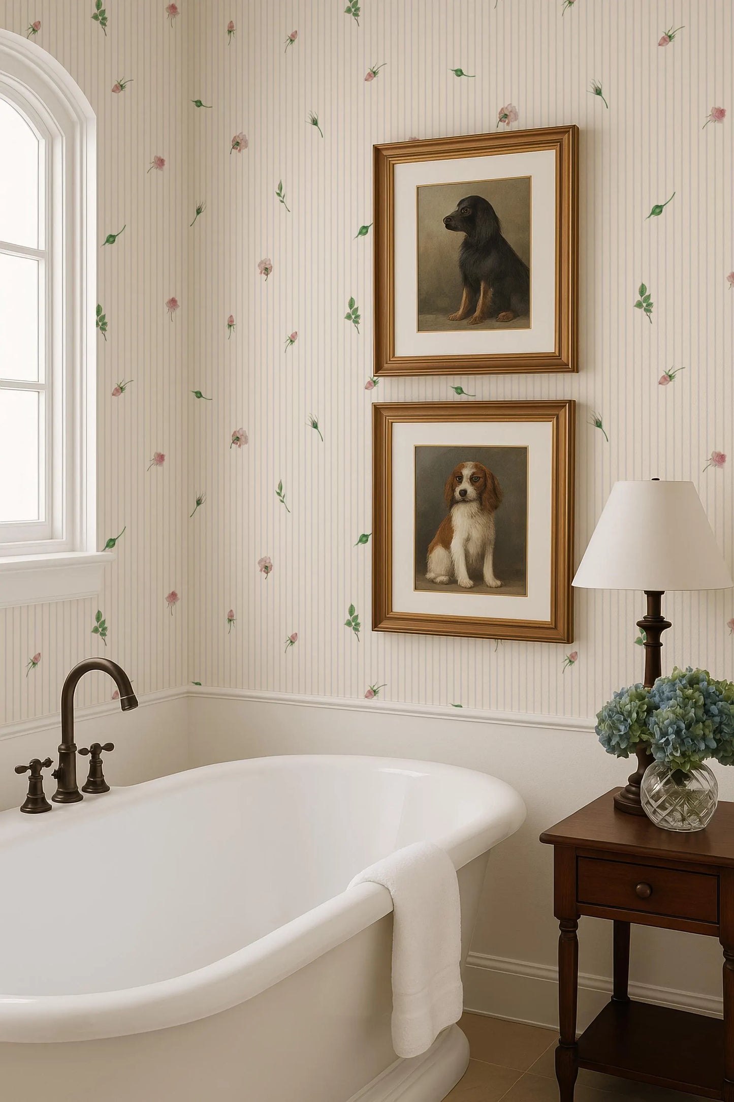 a bathroom with a clawfoot bathtub, framed pictures of dogs, and a lamp on a side table.