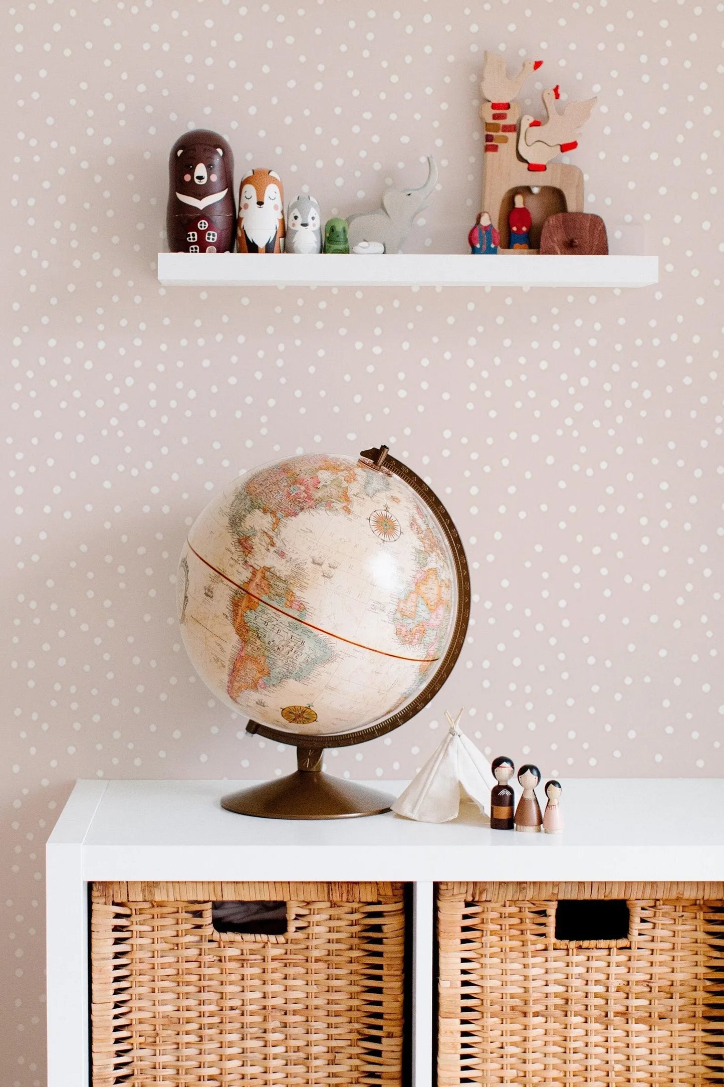 a shelf with various toys and a globe, as well as a small table with wicker baskets and figurines.
