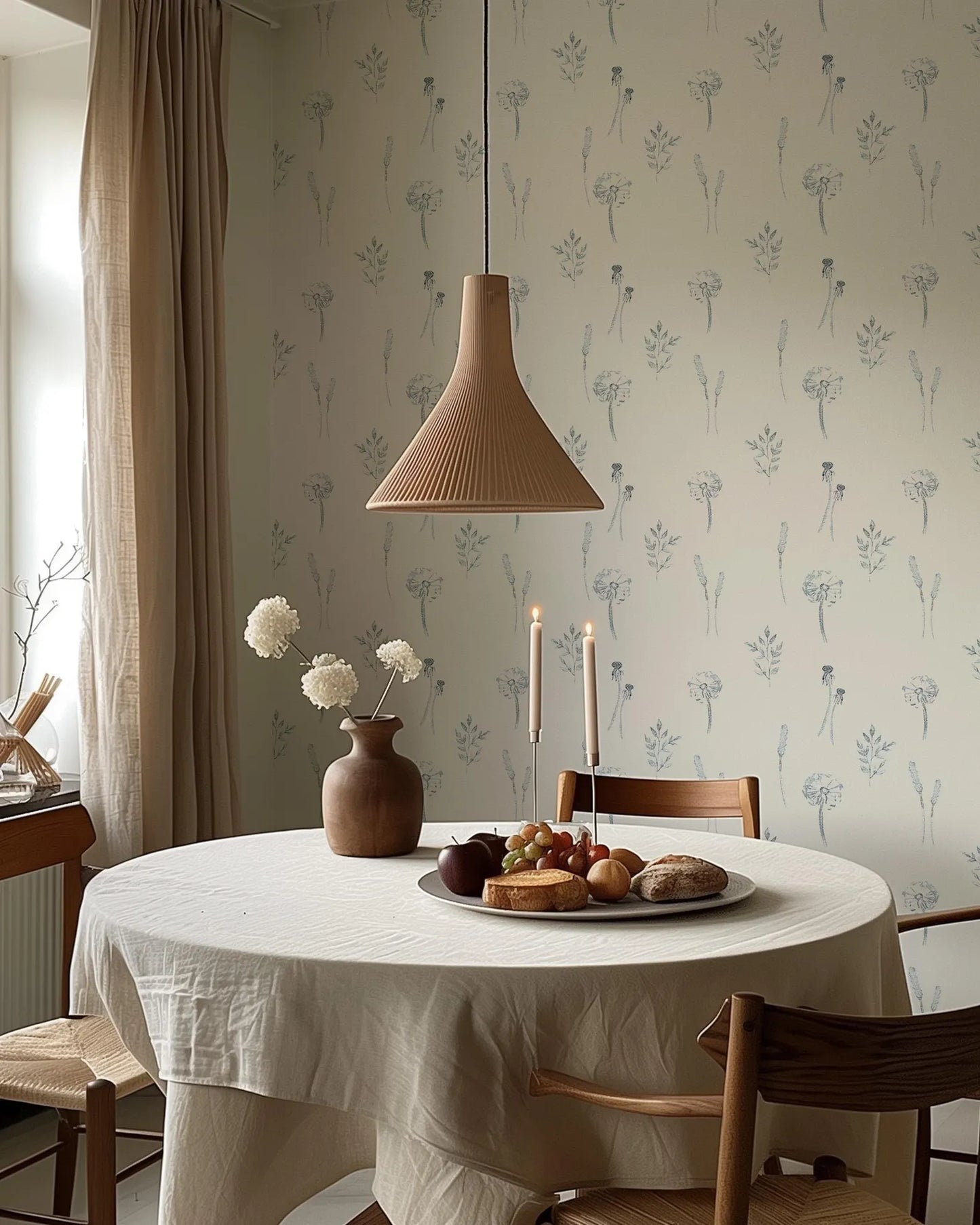a cozy dining scene with a round table set for two, featuring a white tablecloth, a vase of white flowers, a plate of food, and a pendant light hanging above.