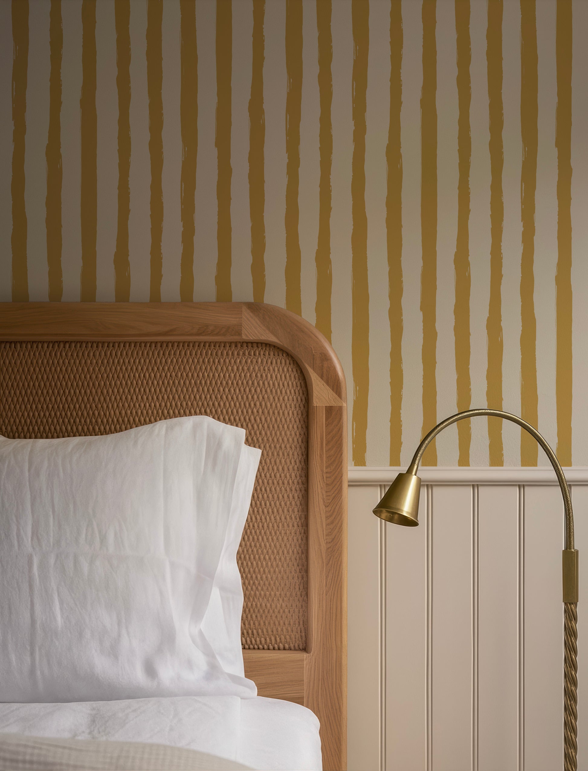 a cozy bedroom scene with a wooden headboard, a white bedspread, and a lamp on a side table.