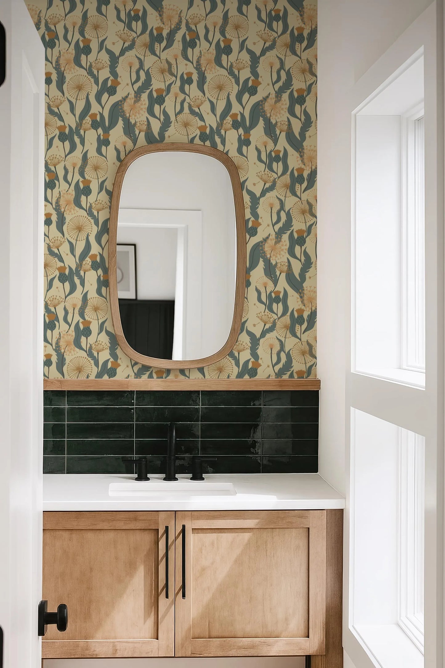 a bathroom with a white sink, a mirror above it, and a green and white floral wallpaper on the wall.