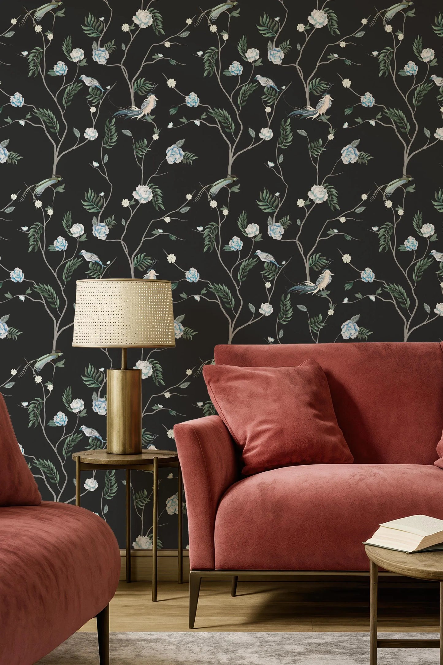 a living room with a red sofa, a gold side table with a lamp, and a black wall with a floral wallpaper.