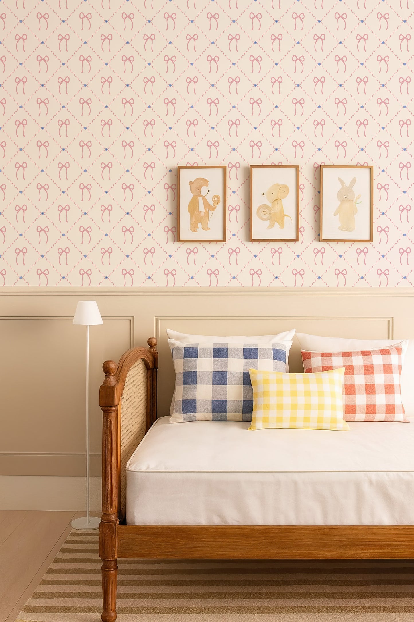 a cozy bedroom setting with a wooden bed frame, a white comforter, and colorful pillows. The walls are decorated with a patterned wallpaper, and there are three framed pictures of animals on the wall. A lamp is also present in the room, providing additional lighting.
