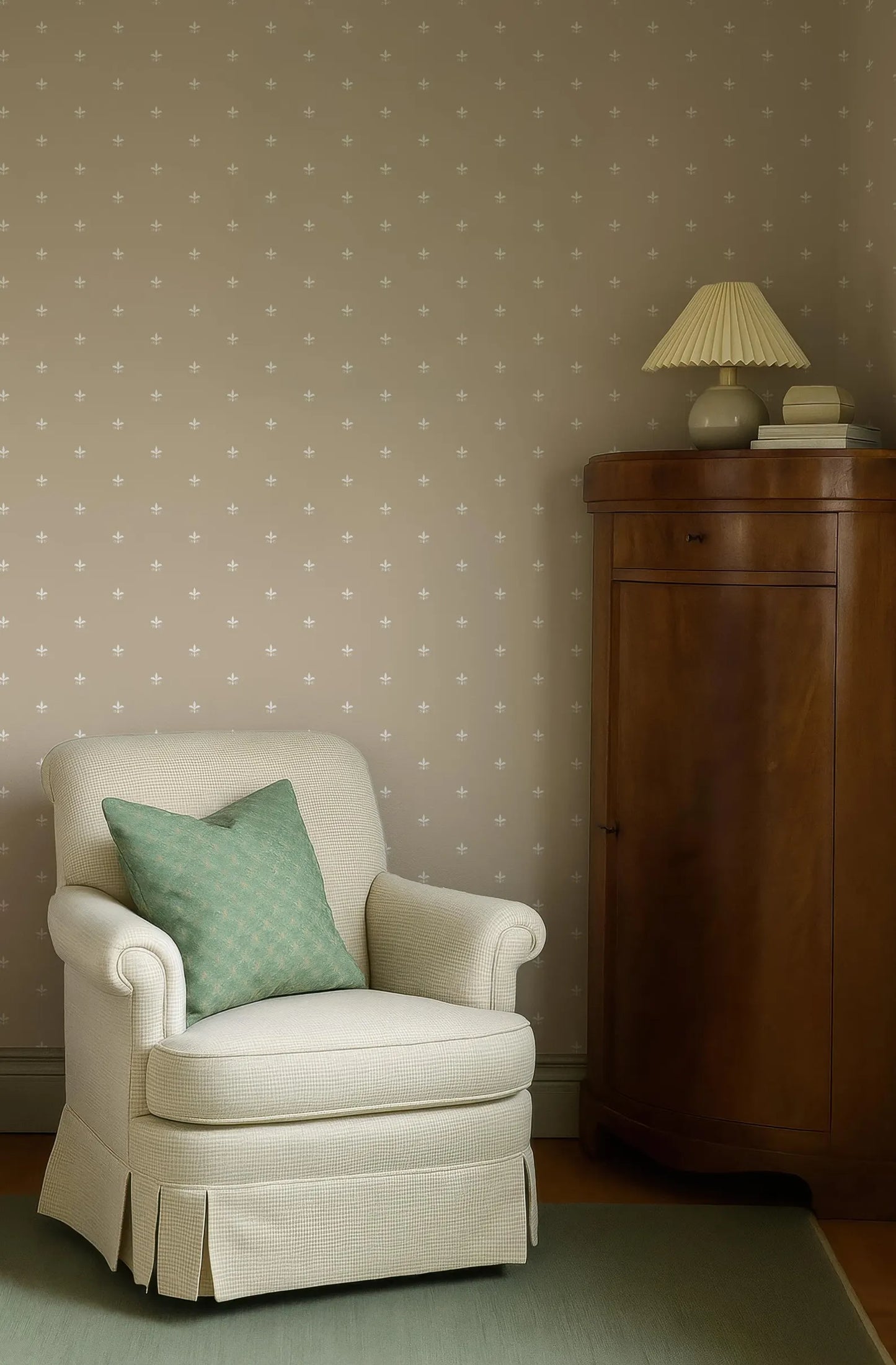 a cozy corner of a room with a white armchair, a wooden cabinet, and a green throw pillow.