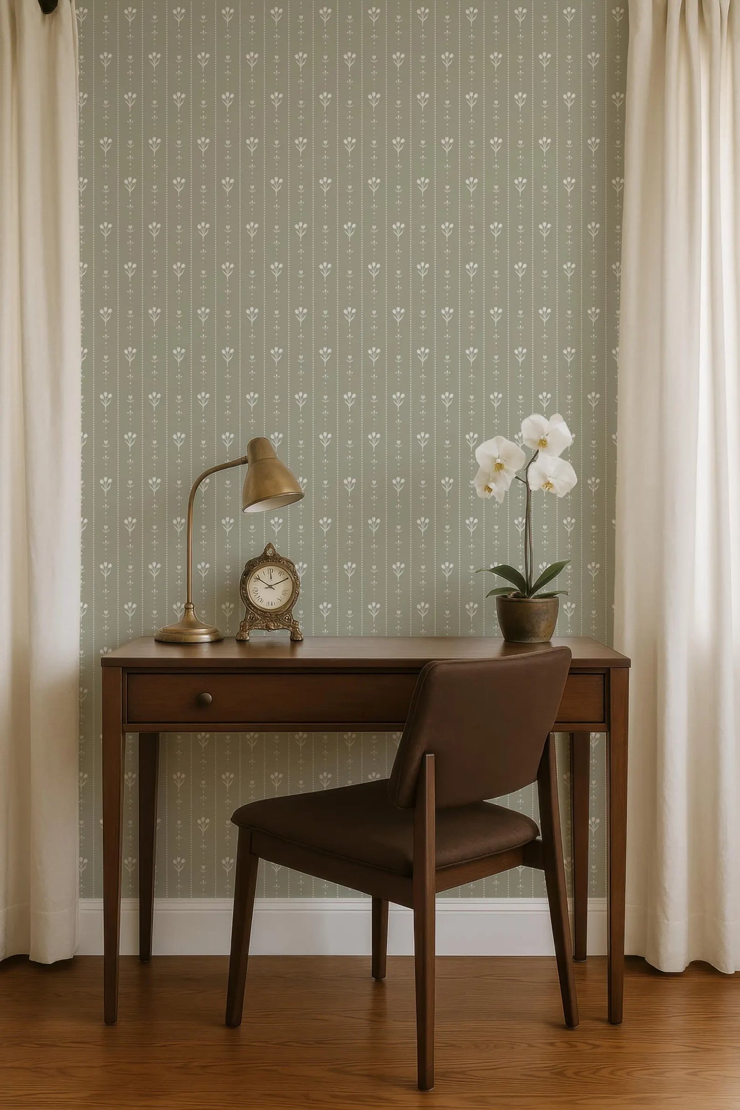 a wooden desk with a lamp, a clock, and a potted plant, situated in front of a wall with a patterned wallpaper.