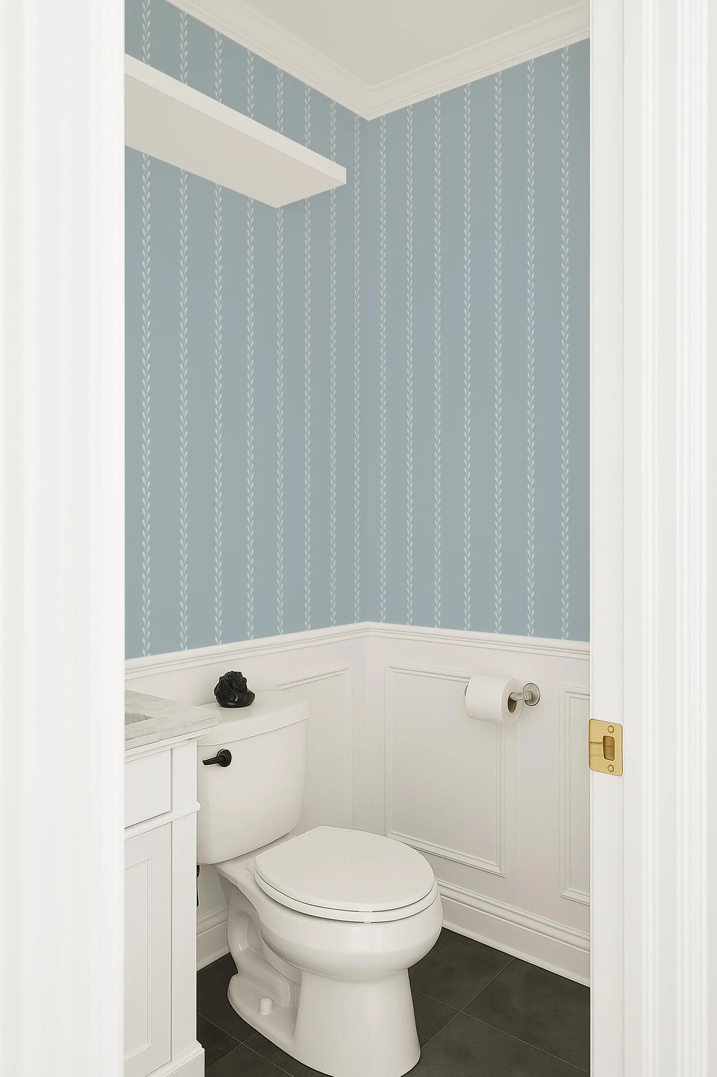 a small bathroom with a white toilet and a white vanity. The walls are covered in blue and white striped wallpaper, and the floor is tiled.