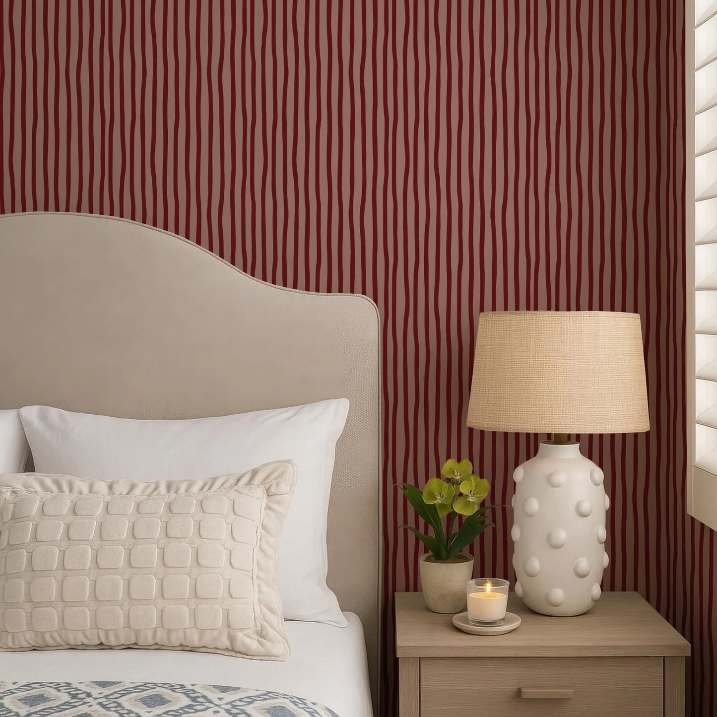 a cozy bedroom scene with a bed, a nightstand, and a lamp. The bed has a beige headboard and white pillows, and the nightstand has a white lamp with a beige shade. There is also a small potted plant on the nightstand.