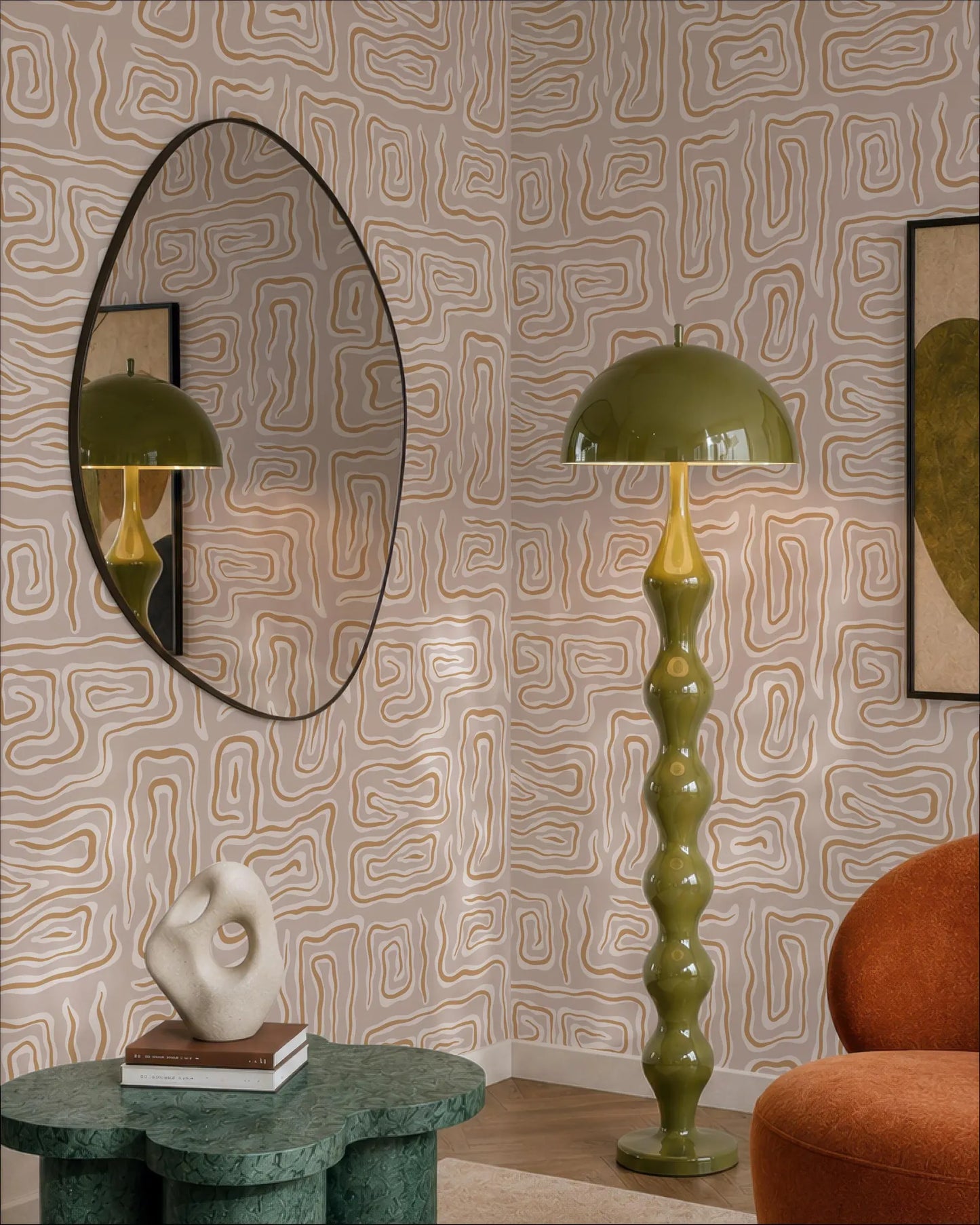 a modern living room with a large mirror, a green floor lamp, and a round table with a sculpture on top. The room has a geometric patterned wallpaper and a red armchair.