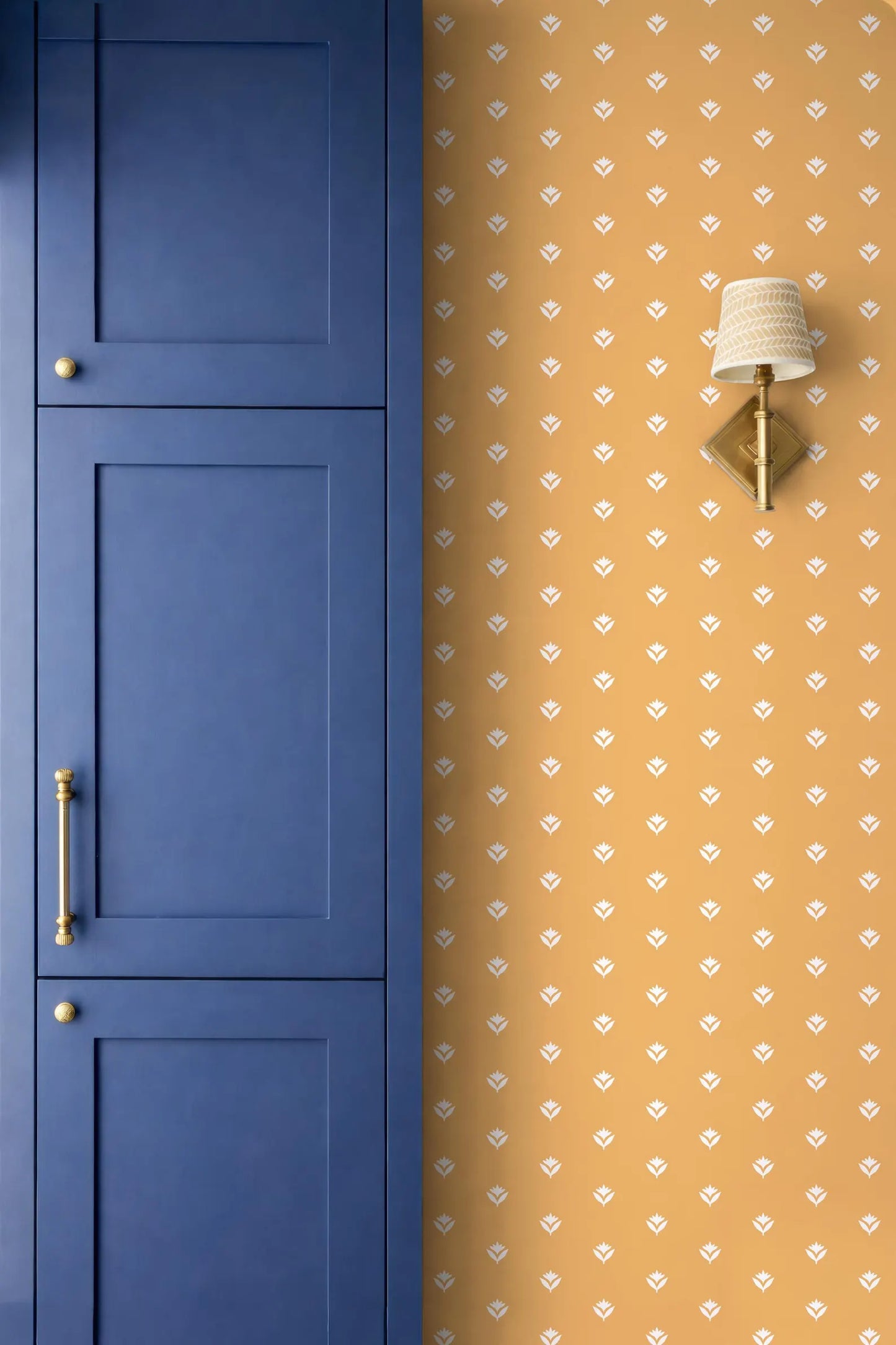 a blue cabinet door and a wall with a patterned wallpaper.