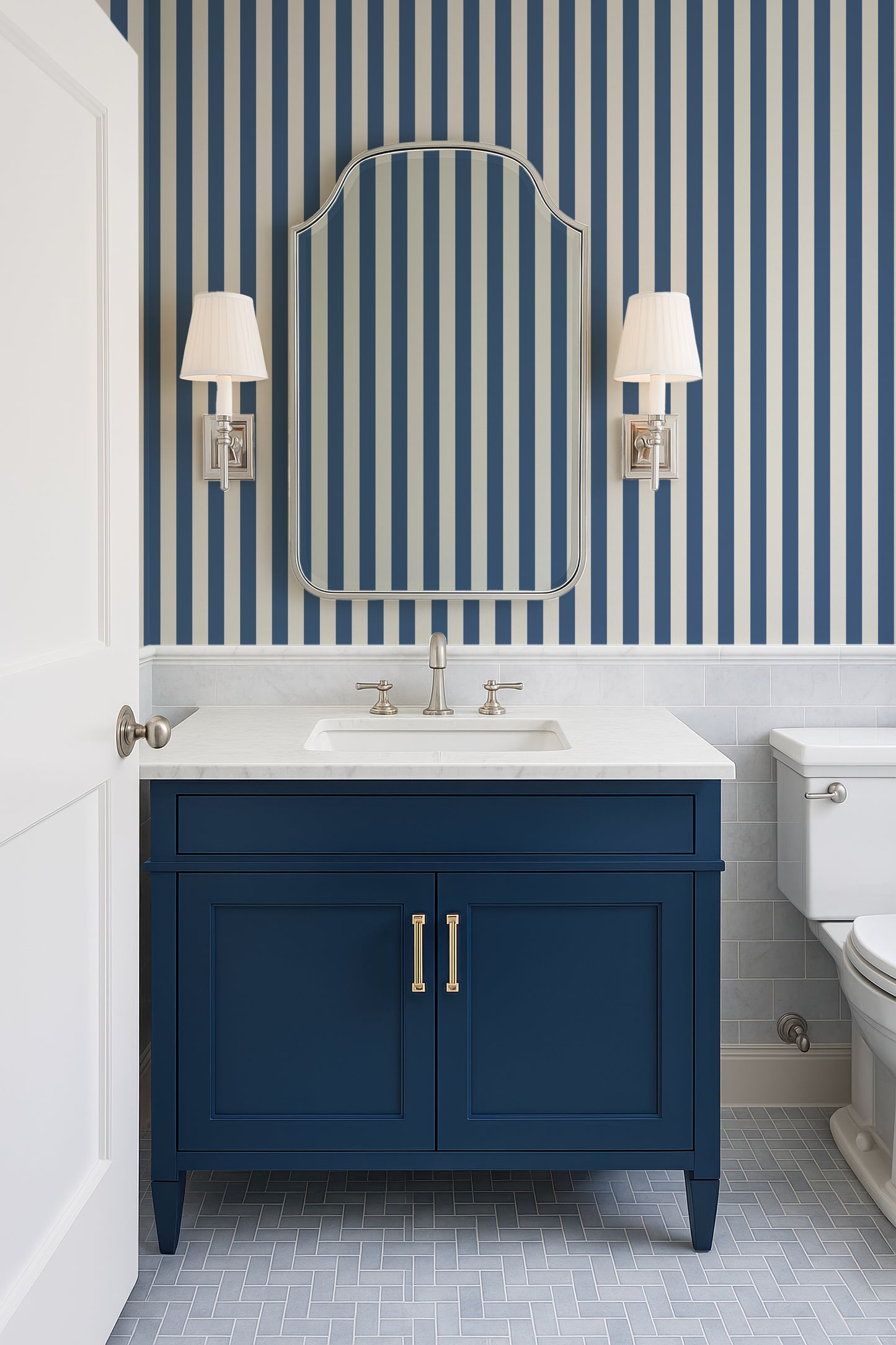 a bathroom with a blue vanity and white fixtures, including a sink and two wall sconces. The walls are striped in blue and white, creating a cohesive and modern design.
