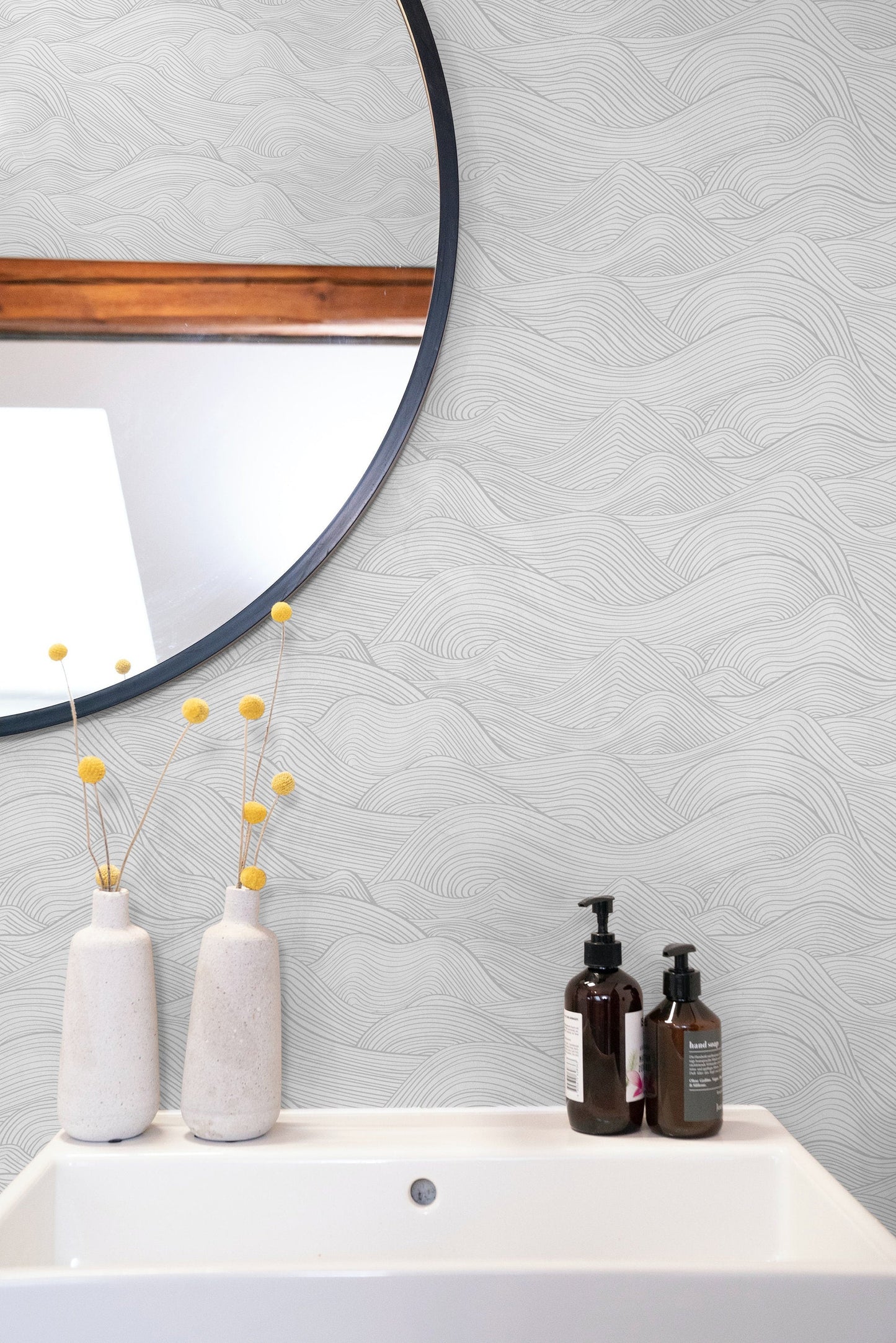 a white sink sitting under a round mirror
