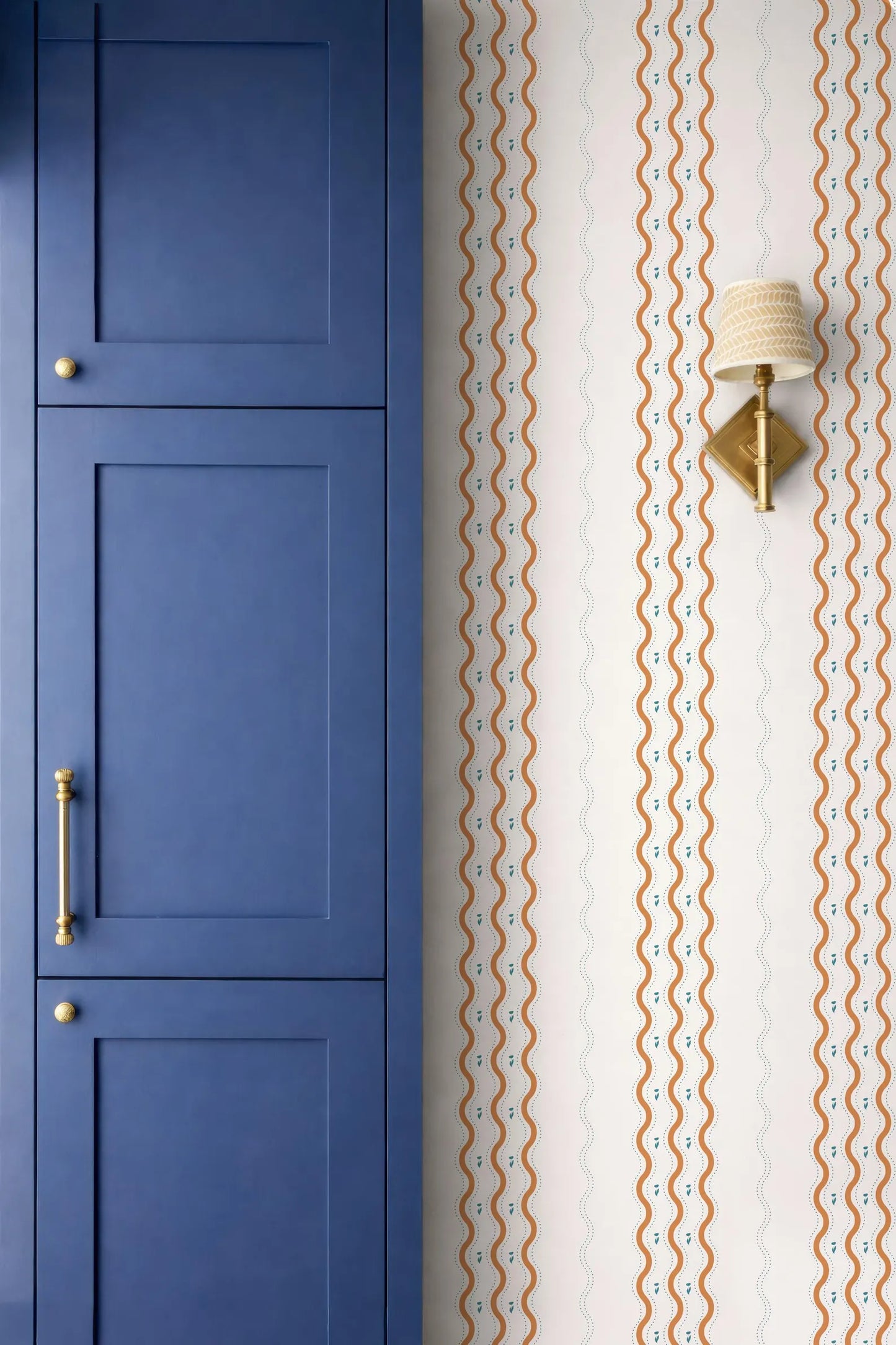 a blue cabinet door and a wall with a patterned wallpaper.