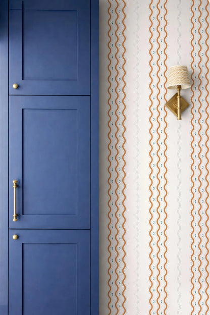 a blue cabinet door and a wall with a patterned wallpaper.