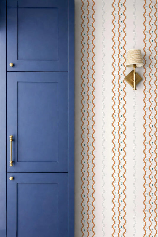 a blue cabinet door and a wall with a patterned wallpaper.