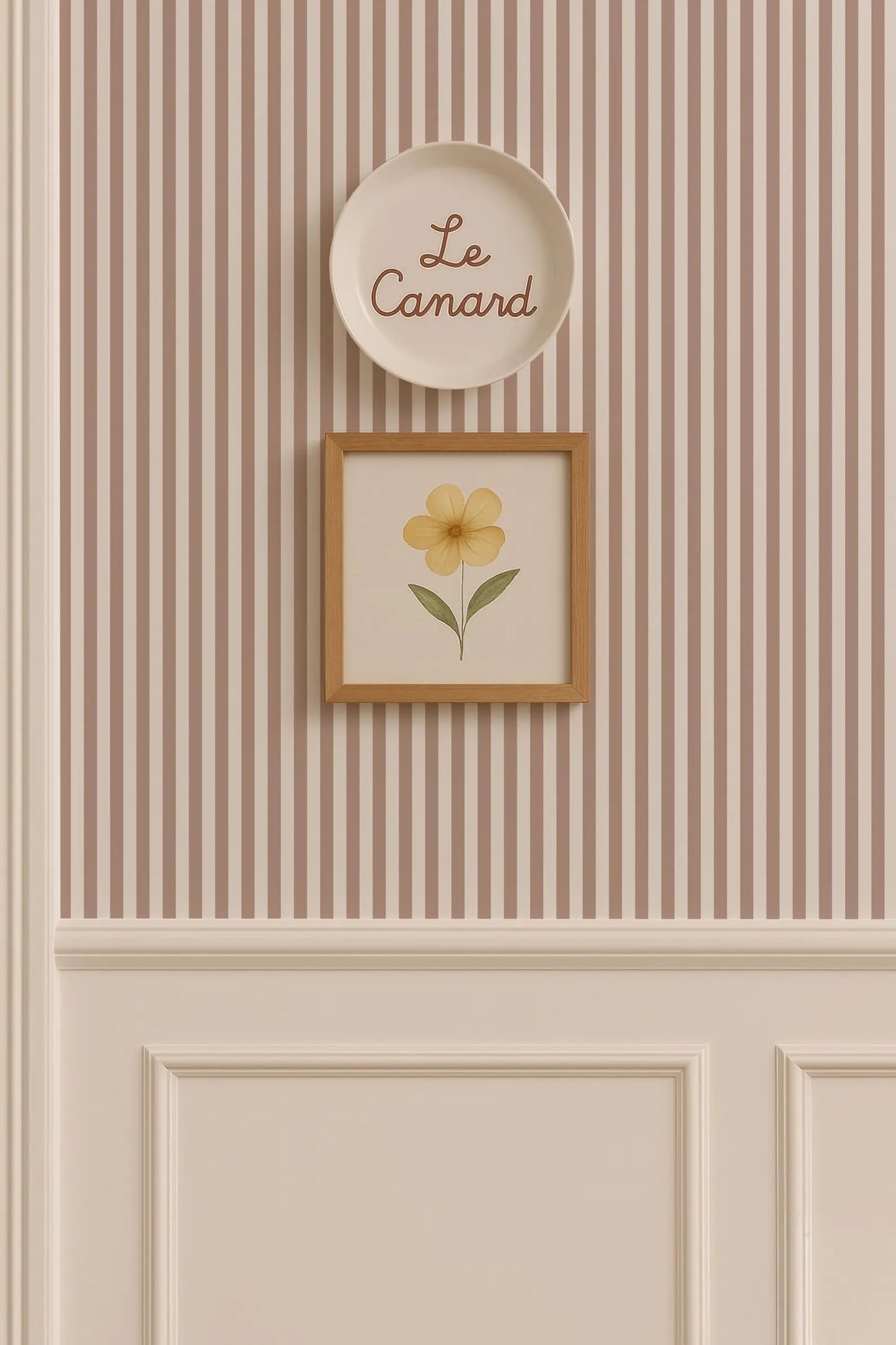 a wall with a framed picture of a yellow flower and a plate with the word "Le Camand" written on it.