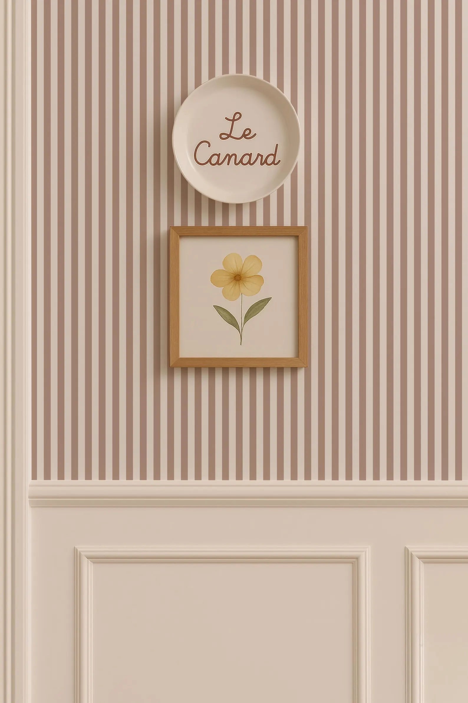 a wall with a framed picture of a yellow flower and a plate with the word "Le Camand" written on it.