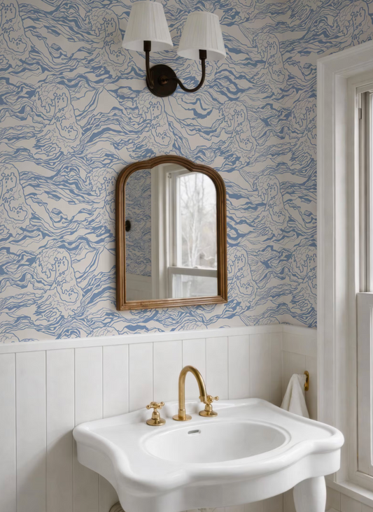 a bathroom with a white sink, a mirror, and a light fixture above it. The walls are covered in a blue and white wallpaper with a wave pattern.