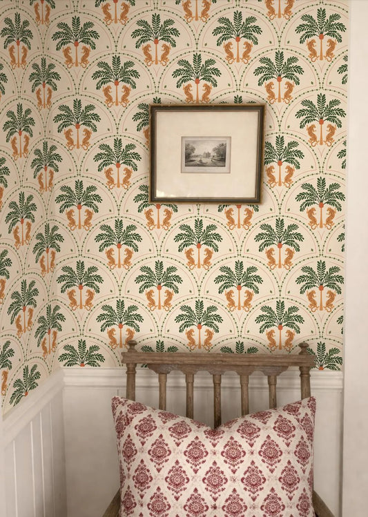 a bedroom with a wooden headboard and a red and white patterned pillow on a bed. The wall behind the bed has a repeating pattern of palm trees and other tropical elements, creating a tropical ambiance. A framed picture is hanging on the wall above the bed.