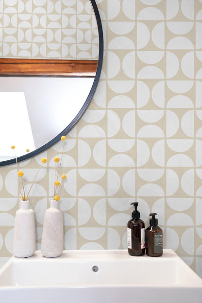 a bathroom setting with a white sink, a round mirror, and a shelf with two bottles of soap and two white vases with yellow flowers.