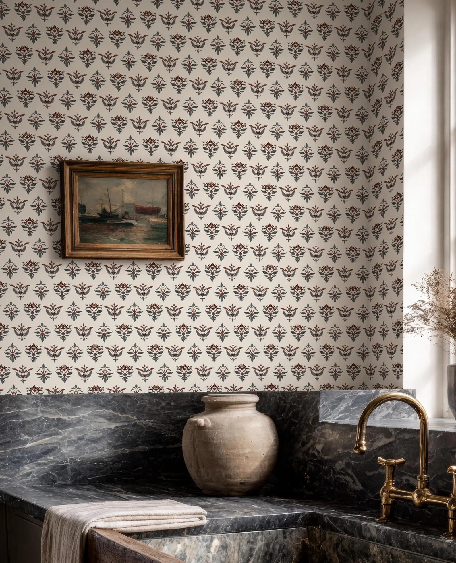 a bathroom with a patterned wallpaper, a framed painting on the wall, a marble countertop, a vase, and a gold faucet.