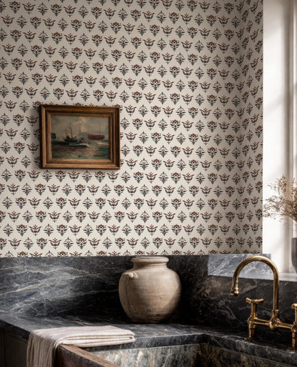 a bathroom with a patterned wallpaper, a framed painting on the wall, a marble countertop, a vase, and a gold faucet.