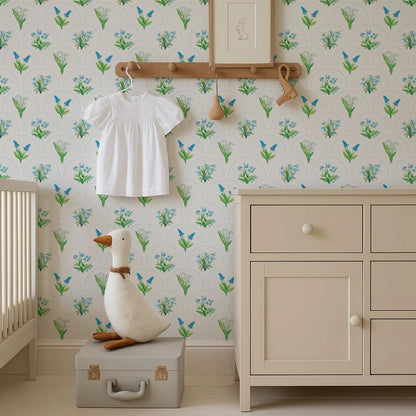 a nursery room with a white dresser, a stuffed duck, and a wallpapered wall with a floral pattern.