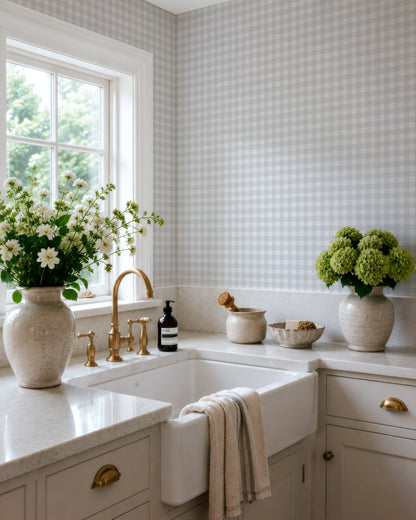 a well-organized kitchen with a white sink, a window, and a vase of white flowers on the counter.
