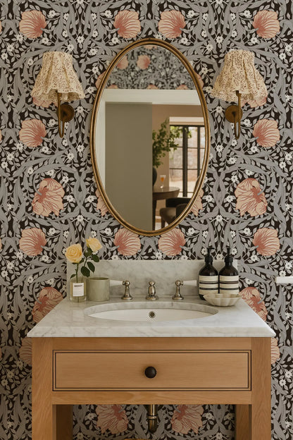 a bathroom with a white marble sink, a wooden vanity, and a large oval mirror with a gold frame. The walls are covered in a floral patterned wallpaper, and there are two lamps with beige shades on either side of the mirror.