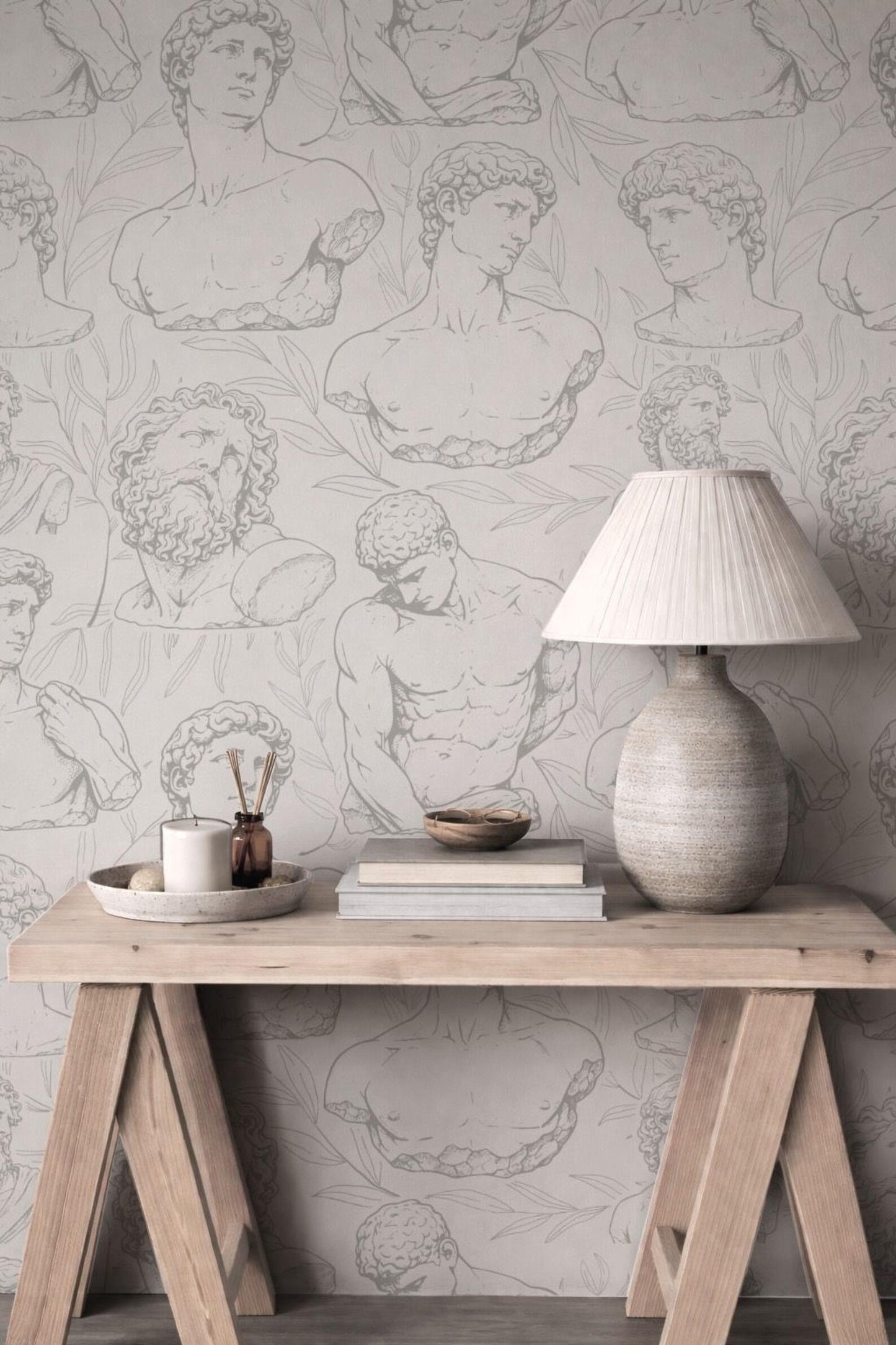 a wooden table with a lamp, a bowl, and some books on it, set against a wall with a repeating pattern of classical human anatomy drawings.