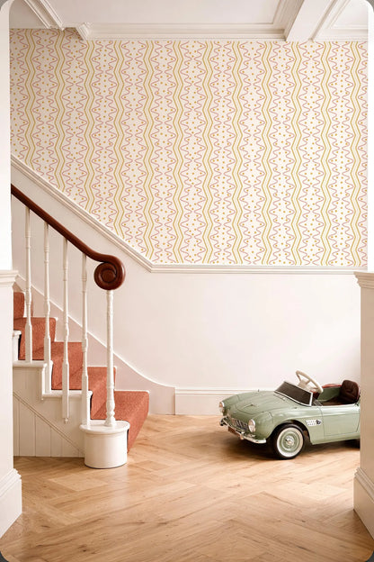 a vintage-style green toy car parked on a wooden floor next to a staircase with a white railing. The walls are adorned with a patterned wallpaper, and the overall scene has a warm and inviting atmosphere.