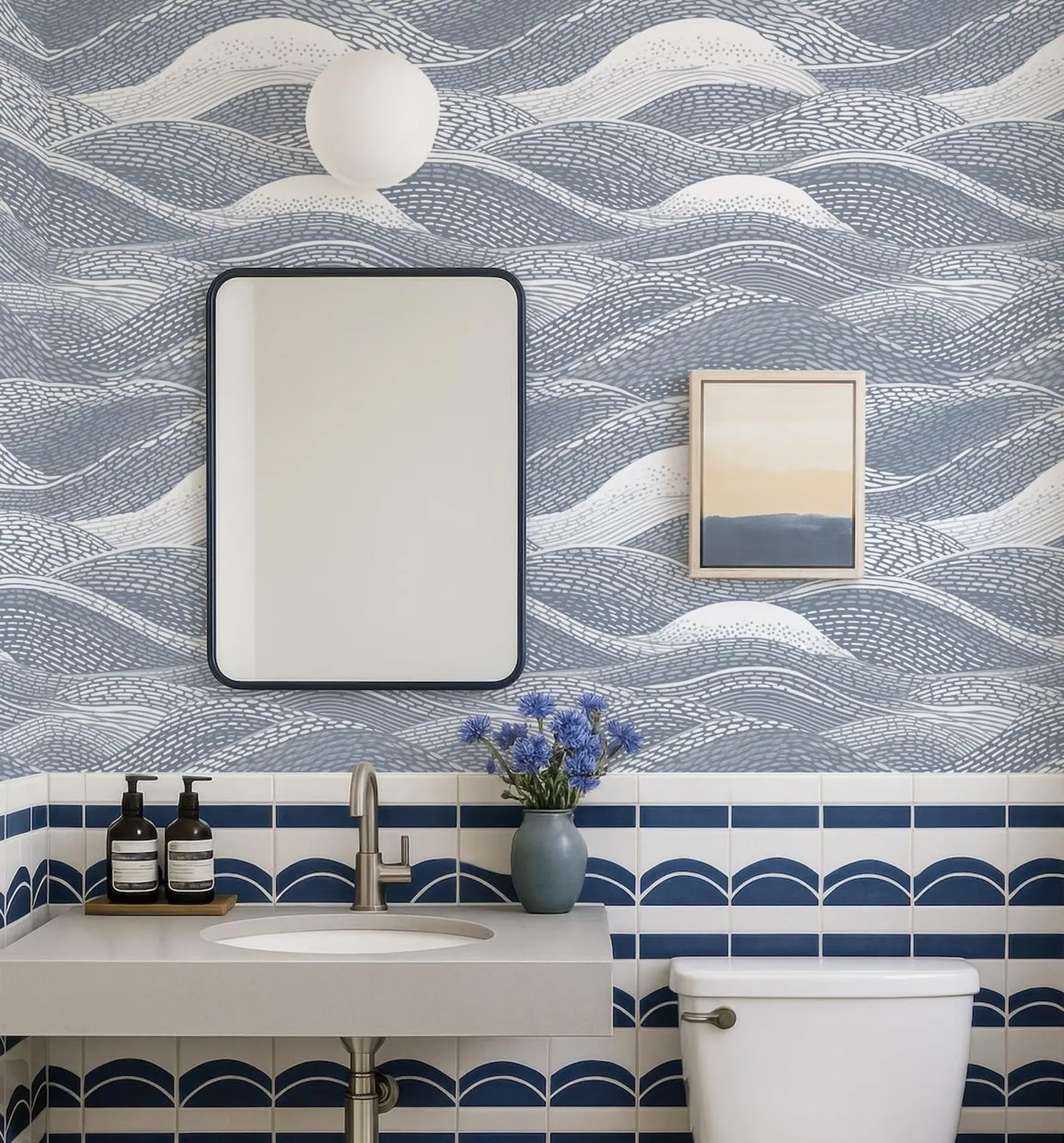 a bathroom with a blue and white color scheme, featuring a white sink, a mirror, and a framed picture on the wall.