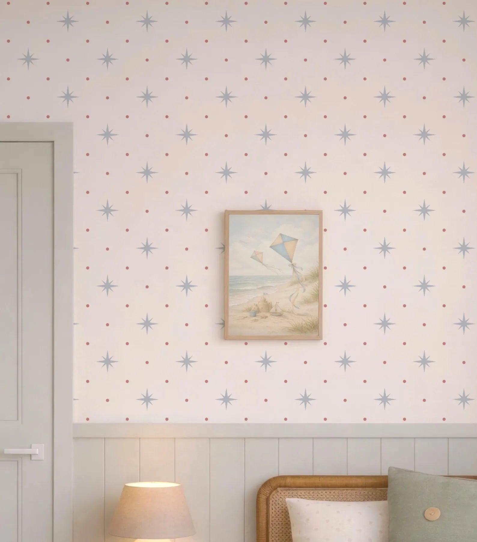 a wallpapered wall with a framed picture of a beach scene, a lamp, and a wooden headboard.