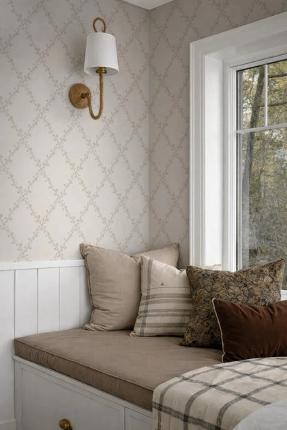 a cozy corner of a room with a white wall, a window, and a bed with a brown and white striped pillow.