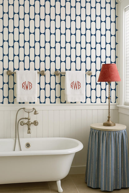 a bathroom with a white clawfoot bathtub, a towel rack with two towels, a red lamp, and a blue and white striped skirt.