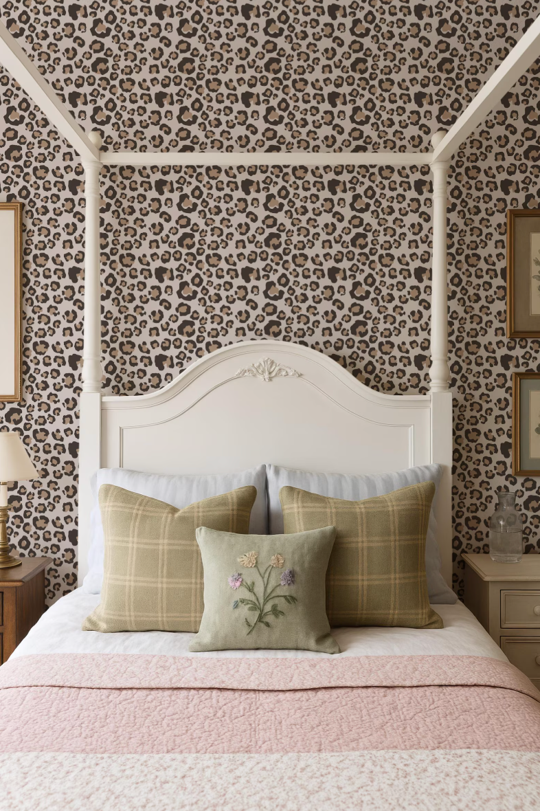 a bedroom with a white canopy bed, a leopard print wallpaper, and a pink and white bedspread. The bed is adorned with three pillows, one of which has a floral design.