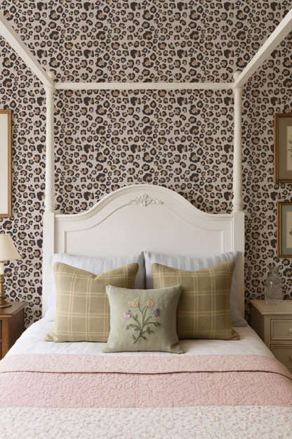 a bedroom with a white canopy bed, a leopard print wallpaper, and a pink and white bedspread. The bed is adorned with three pillows, one of which has a floral design.