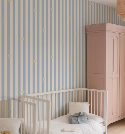 a cozy nursery room with a white crib, a pink wardrobe, and a striped wallpaper with yellow heart patterns.