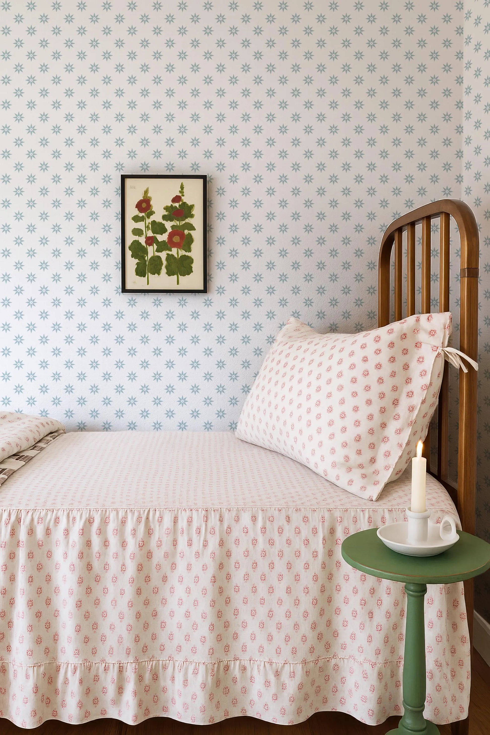 a cozy bedroom scene with a bed, a nightstand, and a framed floral print on the wall.