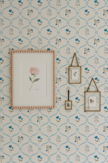a wall adorned with a floral wallpaper pattern, complemented by a framed picture of a pink rose and two framed pictures hanging on the wall.