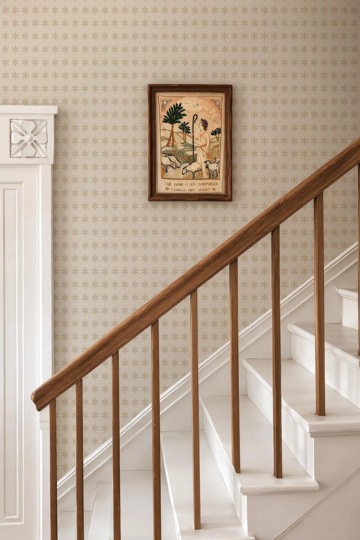 a wooden staircase with a white railing, and a framed artwork hanging on the wall above the stairs.