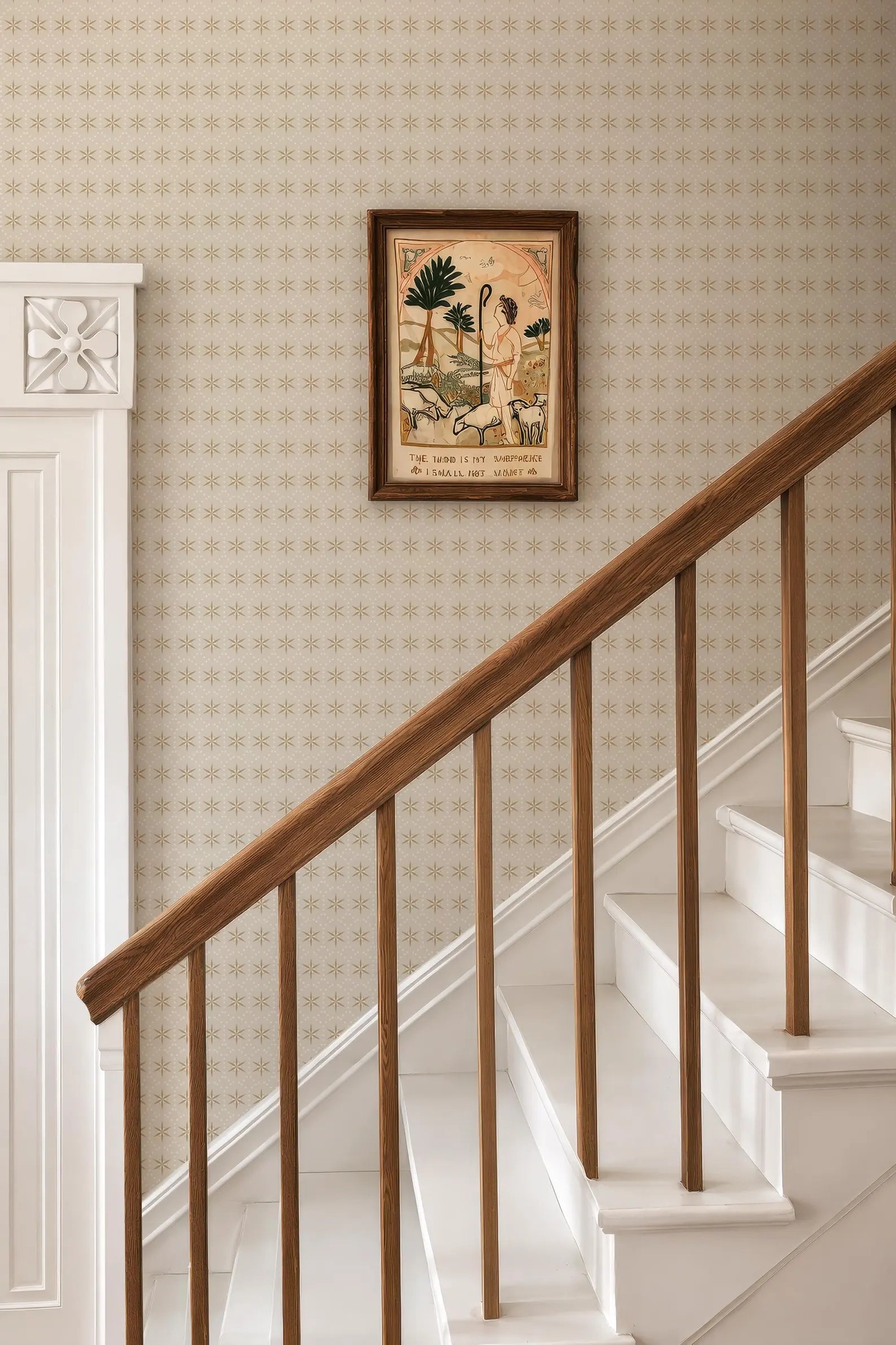 a wooden staircase with a white railing, and a framed artwork hanging on the wall above the stairs.