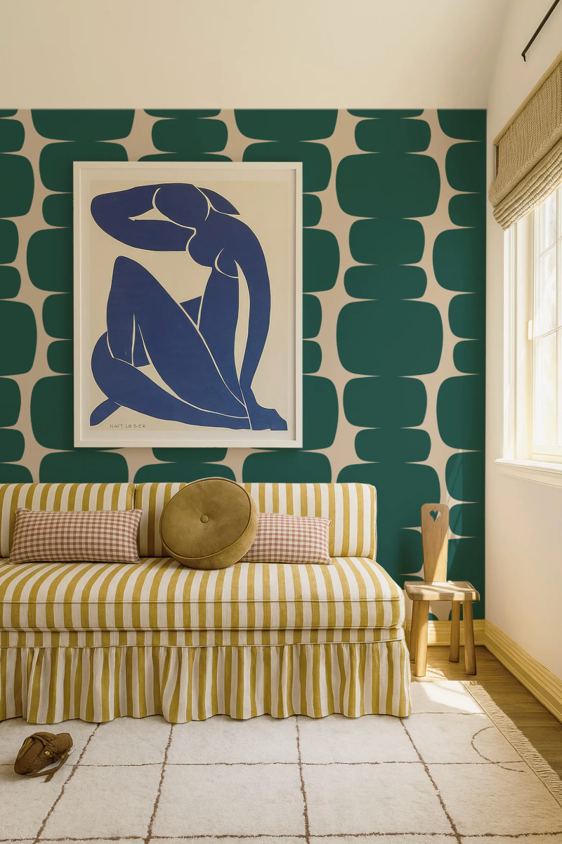 a living room with a striped sofa, a framed artwork of a woman, and a patterned wall behind the sofa.