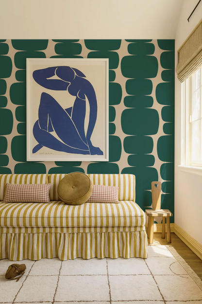 a living room with a striped sofa, a framed artwork of a woman, and a patterned wall behind the sofa.